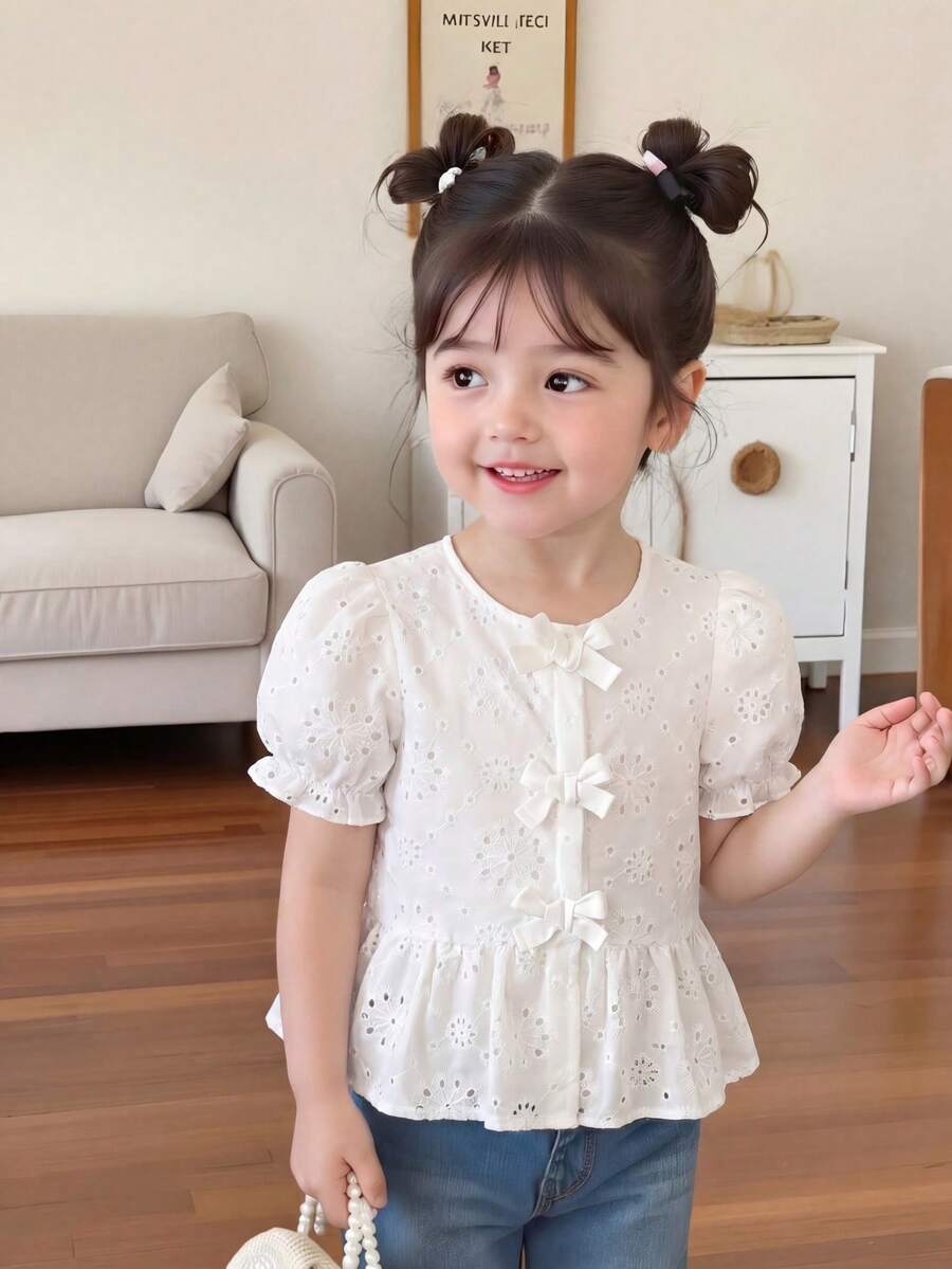 Souflis Souflis 这款欧美风春夏限量版女童白色娃娃领衬衫,纯白色调清新怡人。圆领设计贴合颈部,中袖饰以精致镂空刺绣花卉图案,前襟点缀三个蝴蝶结,更添几分正式感,荷叶边下摆优化了裙长比例。适合上学、户外活动、生日派对等各种场合,是甜美可爱的少女之选。 - 白色 - 查看 1