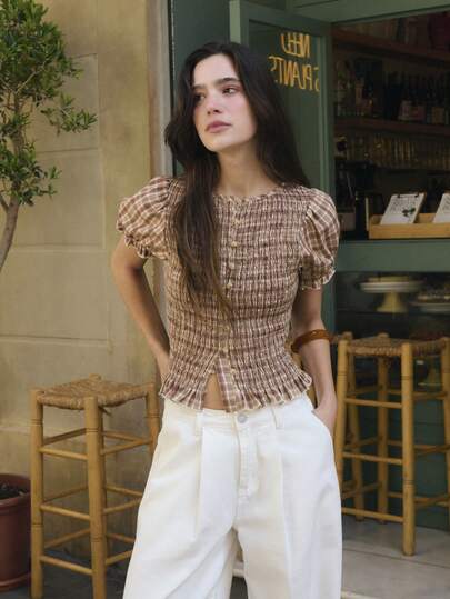 Nöista Áo croptop tay phồng xếp ly kẻ caro màu cà phê có thiết kế ôm sát, co giãn với kỹ thuật may smoking. Tay áo phồng dễ thương và cổ tay/gấu áo xếp ly làm nổi bật vẻ ngọt ngào, nữ tính. Màu sắc nhẹ nhàng mang lại cảm giác thoải mái khi mặc hàng ngày hoặc đi nghỉ mát vào mùa xuân/hè hoặc đầu thu, khiến nó trở thành một món đồ thời trang giản dị và đa năng.