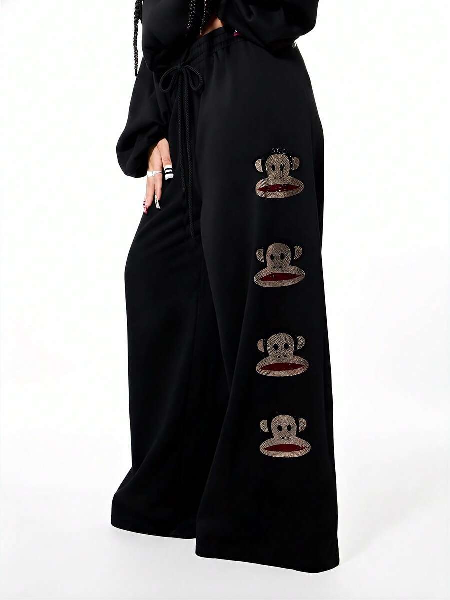 SUMWON X PAUL FRANK SUMWON WOMEN Pantalones de chándal anchos con pierna ancha y gráfico grande para mujer, pantalones de chándal casuales con aplicación de mono de strass y cordón - Negro - Ver 1