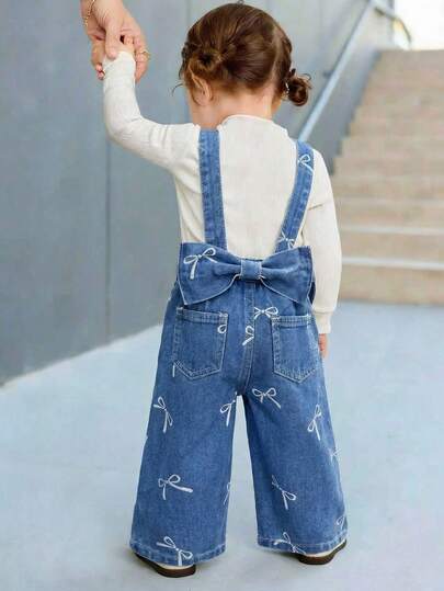 Quần yếm denim màu xanh dương cho bé gái, có nơ trang trí, kiểu dáng rộng rãi.