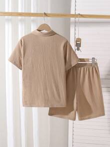 SHEIN Vacaura Bộ đồ đôi cho bé trai gồm áo sơ mi ngắn tay và quần short dệt kim kẻ sọc dọc, chất liệu pha trộn, thân thiện với da và thoáng khí. Áo có thiết kế kẻ sọc dọc nhiều màu với cổ áo nhỏ và tay ngắn; quần short có chun co giãn. Phong cách thường ngày phù hợp cho kỳ nghỉ, đi nhà trẻ, đi biển, v.v. Có thể mặc cả bộ hoặc riêng lẻ để tạo nên một bộ trang phục trẻ em năng động, tươi sáng, một bộ đồ thời trang cho năm học mới. - Màu Khaki - Xem 2