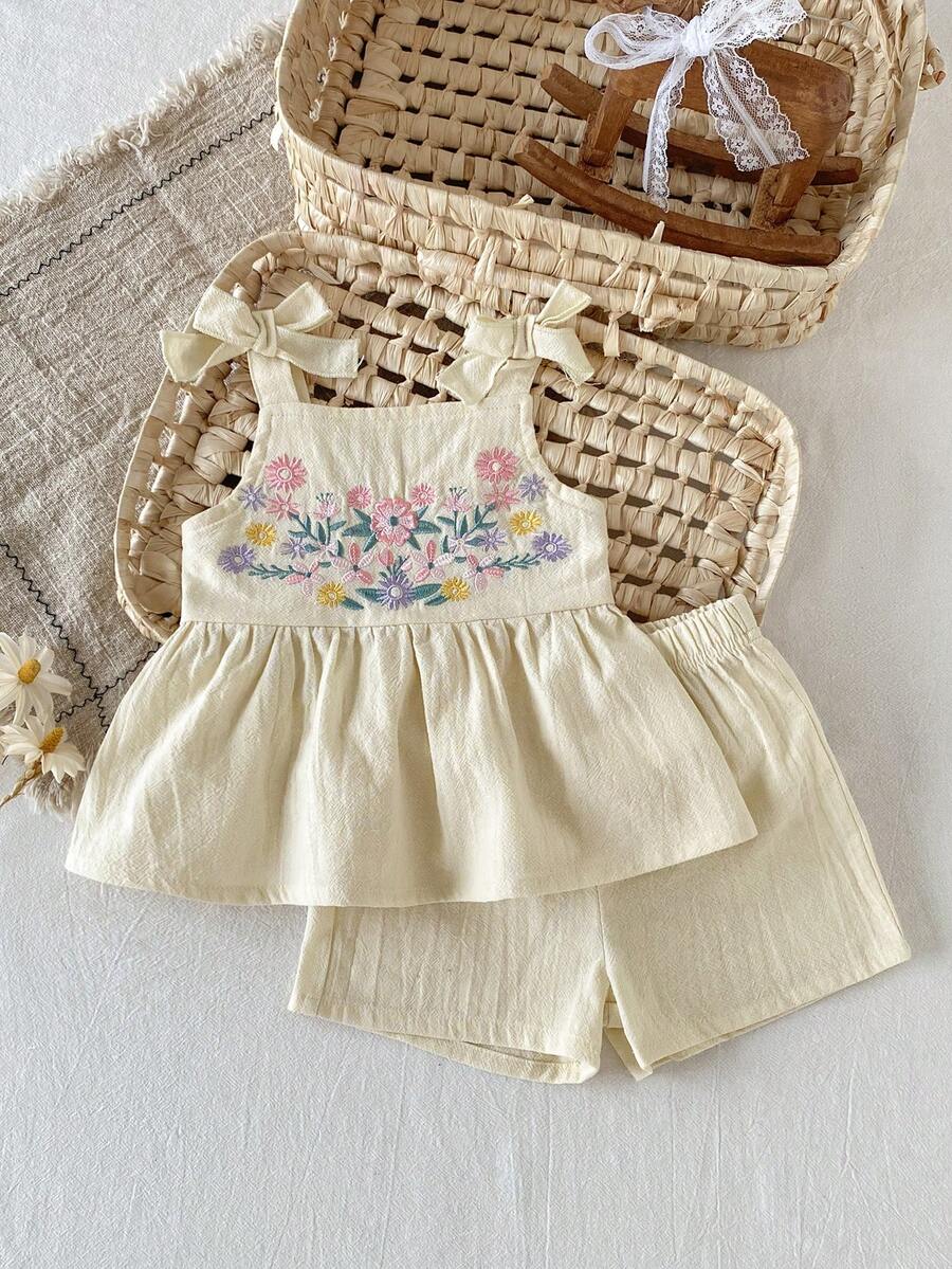 SHEIN 女宝宝假日休闲装，粉色吊带上衣和短裤夏季两件套！采用针织提花面料，独特的提花设计提升了服装的艺术感，上衣下半部分的裙摆设计和肩部的蝴蝶结装饰展现了小女孩的纯真甜美。无论是阳光沙滩、热闹的游乐场还是温馨的家庭聚会，这套服装都是各种派对活动的理想之选。