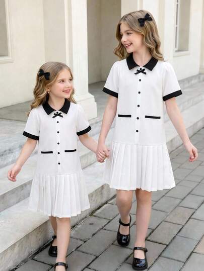 SHEIN Đầm bé gái dáng lửng, cổ bẻ, thắt eo, màu be chủ đạo phối cổ áo đen tương phản, nơ, cúc phía trước và chân váy xếp ly, thanh lịch nhưng vẫn trẻ trung, tay ngắn, thích hợp mặc vào mùa xuân/hè. Phù hợp cho các hoạt động ở trường, tiệc sinh nhật, họp mặt gia đình, đi làm, v.v. Đầm hè ngọt ngào, thanh lịch.
