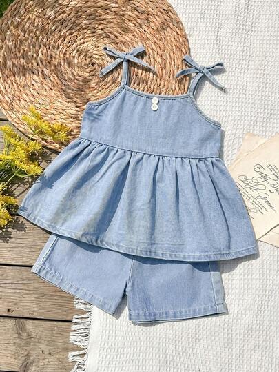 Bộ đồ denim dáng rộng màu xanh nhạt cho bé gái, áo không tay buộc dây vai bèo nhún kết hợp với quần short denim dáng chữ A rộng rãi có chun co giãn, thời trang cho mùa xuân và hè.