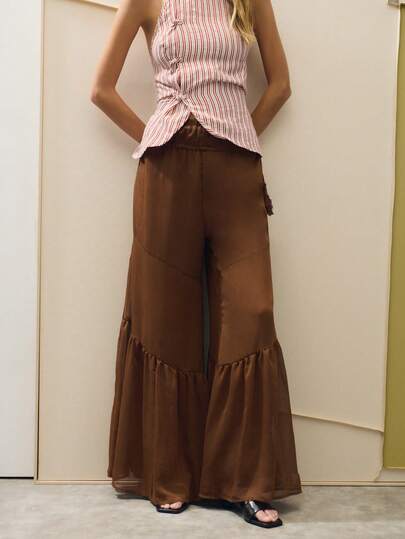 Nöista Pantalones anchos de pata ancha en color marrón con un bajo con volantes, que exudan elegancia femenina y estilo casual. Hechos de una tela ligera, perfectos para los días calurosos de verano, el color es versátil y resalta la textura. Una opción cómoda y elegante para unas vacaciones. Combínalos con bailarinas o sandalias para un look relajado de vacaciones.
