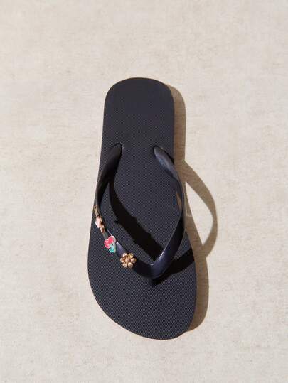 Nöista A Casual Navy Blue Flip-Flop Featuring A Lightweight Sole And Glossy Straps Adorned With Small Decorative Charms For A Fun, Playful Touch.
