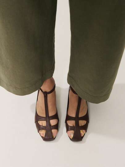 Nöista Mẫu sandal đế bằng cổ điển bằng da màu nâu, thiết kế quai chữ T với mũi kín và khóa điều chỉnh ở mắt cá chân, tạo nên vẻ ngoài thanh lịch vượt thời gian.