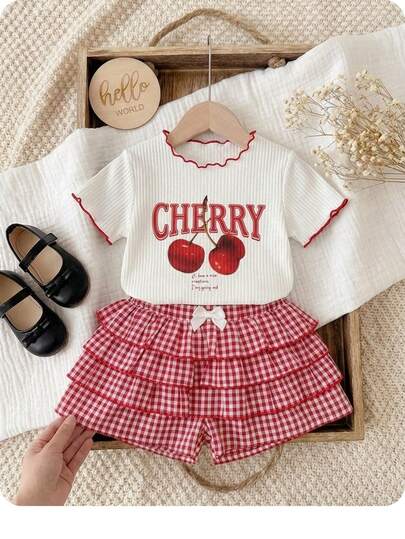 SHEIN Bộ 2 món cho bé gái, kiểu dáng thường ngày, đa năng, gồm áo thun ngắn tay và quần short kẻ caro viền bèo nhún, họa tiết quả anh đào.
