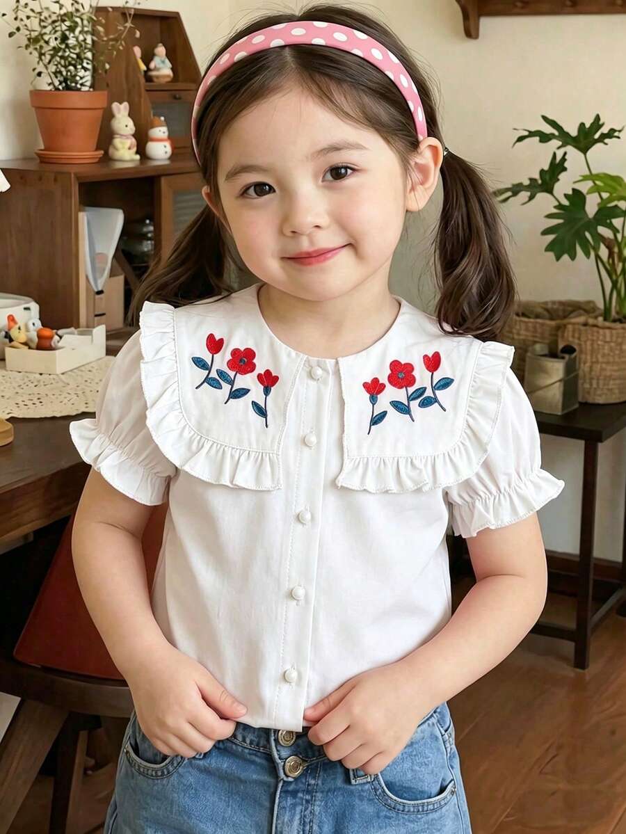 Souflis Souflis 夏季儿童粉色短袖蘑菇纽扣衬衫,大翻领设计,领口和袖口饰有荷叶边,甜美可爱。正面饰有红色花朵刺绣和绿色叶子点缀,增添俏皮感。门襟采用白色蘑菇纽扣,简约实用。可爱俏皮的风格,适合小女孩日常穿着。 - 白色 - 查看 1