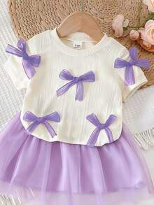 SHEIN Bộ 2 món áo thun cho bé gái, áo thun ngắn tay màu mơ dệt kim trang trí nhiều nơ tím, kết hợp với chân váy lưới cùng màu, kiểu dáng ngọt ngào và dễ thương, tối giản và thời trang, thoải mái cho những buổi đi chơi thường ngày vào mùa hè. - Màu tím - Xem 5