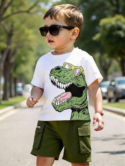 SHEIN 2 st/set Young Boys löst sittande, avslappnad gatutopp med dinosaurietryck och sidotryck, i kombination med cargoshorts i kontrastfärg. Grafiskt tryckt topp och matchande shorts bildar en dynamisk, sportig gatustil, perfekt för vardagliga och sportiga tillfällen för pojkar.