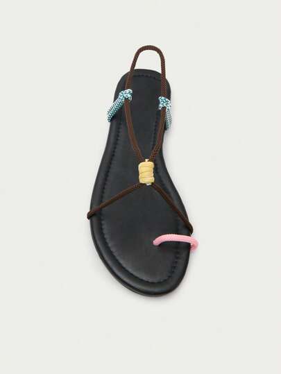 A Minimalist Flat Sandal With A Black Sole, Featuring Multicolored Rope Straps And A Central Knot Detail For A Casual, Handcrafted Look.