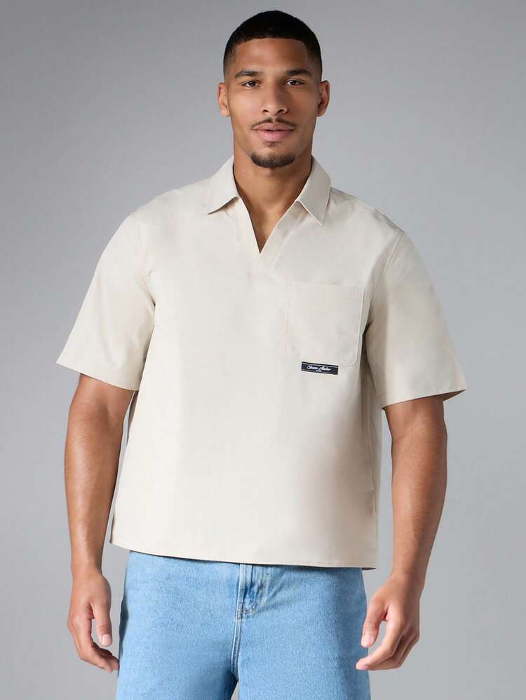 Camisa de manga corta con cuello y bolsillo en el pecho, con parche de logo tejido, ajuste holgado y casual para el verano