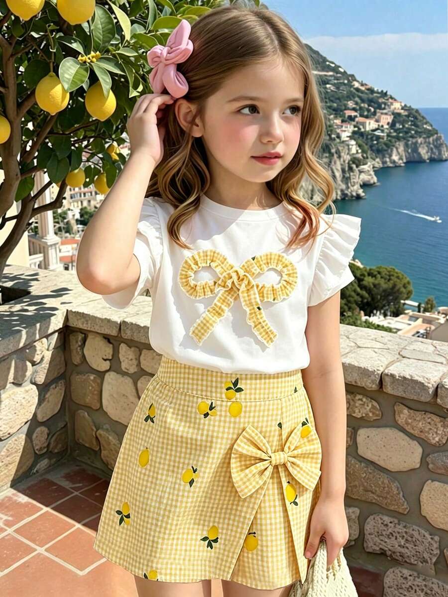 Elladie kids Bộ đồ thường ngày 2 món cho bé gái: Áo cổ tròn ôm dáng mềm mại, dáng suông, phối vàng và trắng kẻ caro, tay bồng, nơ, gồm áo vàng chanh và quần kẻ caro có nơ.