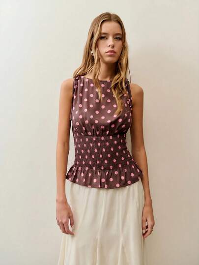 Nöista Blusa de lunares en tela semitransparente marrón con puntos rosas, con cintura fruncida para un ajuste favorecedor y volante suave en el bajo. Diseñada con detalles de lazos en los hombros, es ligera y femenina, perfecta para primavera y verano, ideal para looks casuales, de vacaciones o de uso diario y divertido.