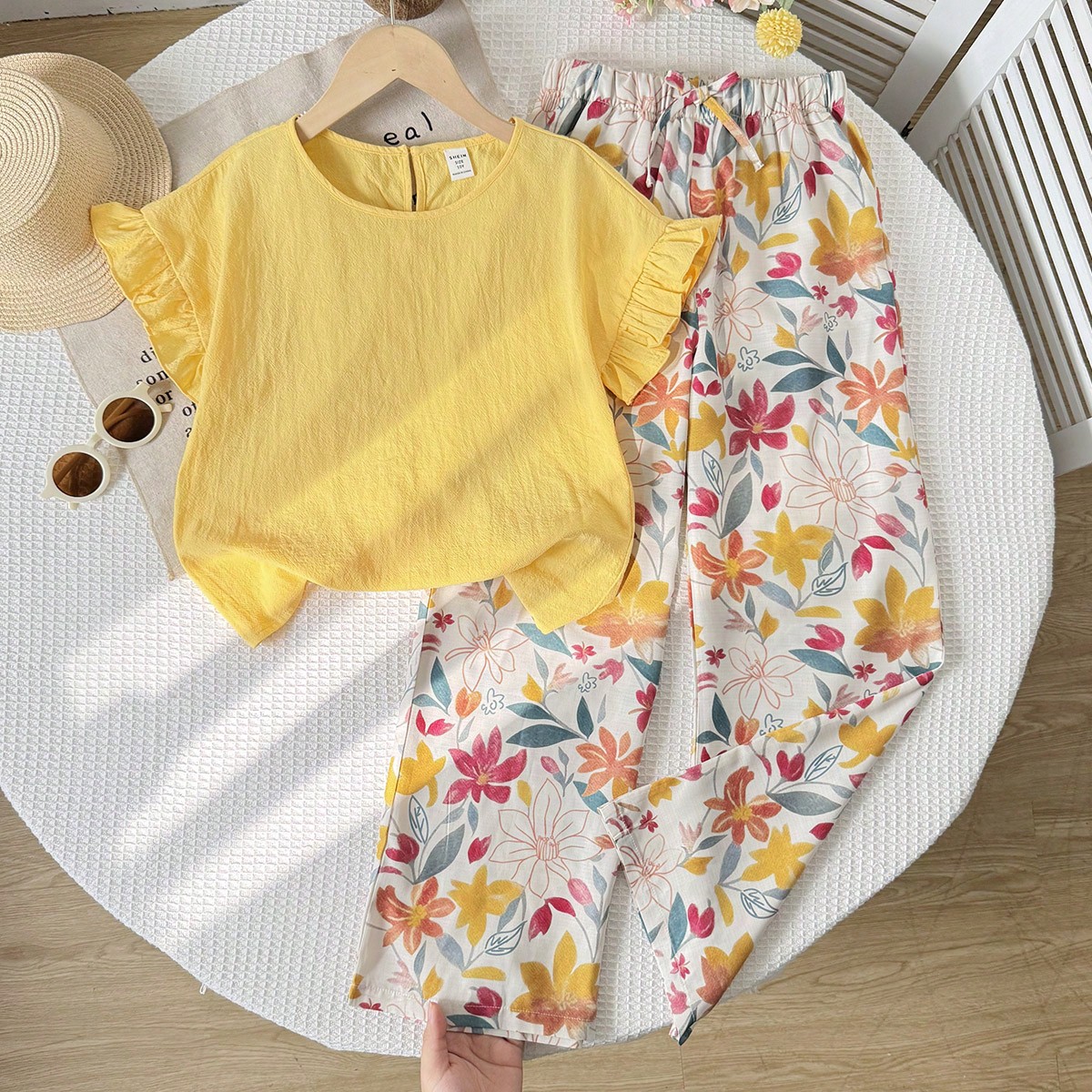 Conjunto informal de niña preadolescente con camiseta de manga de vuelo de unicolor tejida y pantalones con estampado floral diminuto