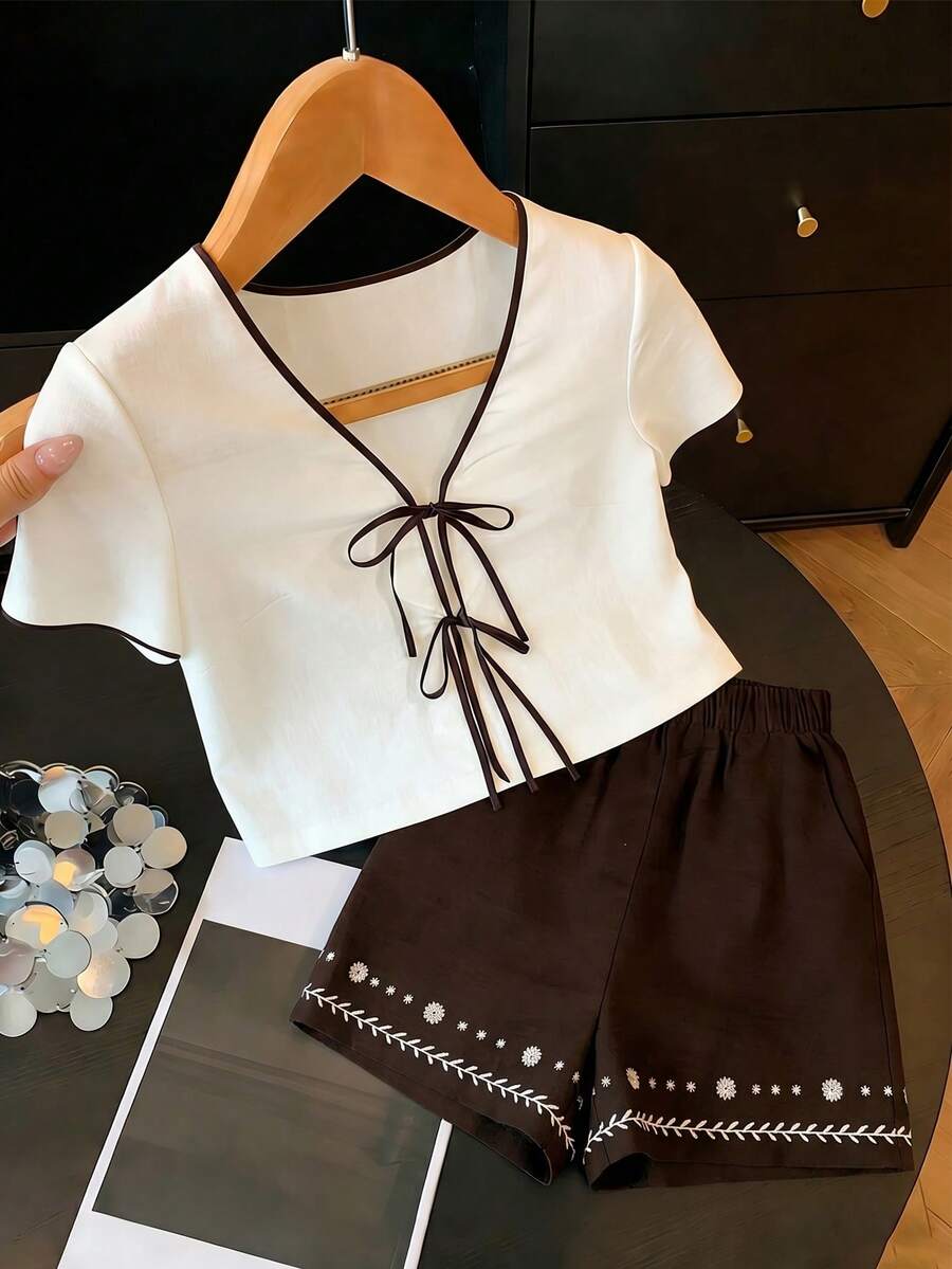 SHEIN Franclia Bộ đồ nữ thường ngày gồm áo tay ngắn cổ chữ V màu trắng, chất liệu giả lanh, họa tiết chần bông, phối viền tương phản, thắt nơ tre, kết hợp với quần short màu nâu đậm, chất liệu bền chắc, thoải mái, phù hợp cho công sở. - màu nâu - Xem 1