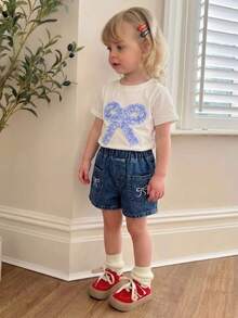 SHEIN Genkimix Kids Outfit estivo casual e carino per bambine e ragazze: top bianco a maniche corte con ricamo a fiocco, pantaloncini di jeans blu con tasche e ricami - Bianco - Visualizzare 1