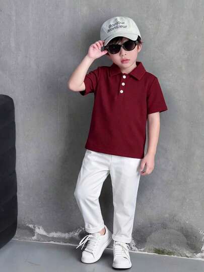 Genkimix Kids 两件套幼儿男童校服POLO衫和长裤，春夏款。上衣为藏蓝色短袖POLO衫，白色领子，两粒纽扣，设计简洁利落，右侧有一个小口袋。裤子为浅蓝色牛仔裤，经典百搭。整体风格清新休闲，适合儿童日常活动，如上学或户外玩耍。