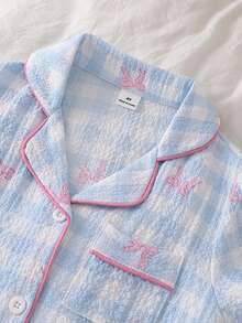 SHEIN Vintaside Kids 这款两件套女童夏季短袖睡衣，上衣采用翻领纽扣前襟设计。这款休闲家居服采用柔软顺滑的泡泡纱面料，饰以蓝白格纹图案、粉色撞色滚边、迷人的蝴蝶结印花和可爱的樱桃图案，营造出俏皮舒适的氛围。 - 藍色 - 查看 5