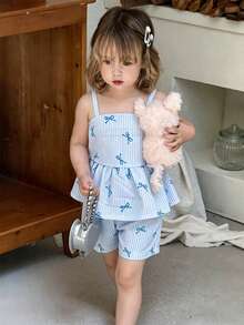 SHEIN Vintaside Kids 这款女童夏季粉白条纹露背吊带短裙套装，甜美俏皮，充满度假风情；采用梭织面料，版型合身。整套服装印满粉色小蝴蝶结和条纹图案，裙摆饰有荷叶边，活泼优雅。适合日常出行、上学、海滩度假、参加派对活动以及休闲放松等各种场合。 - 淺藍色 - 查看 4