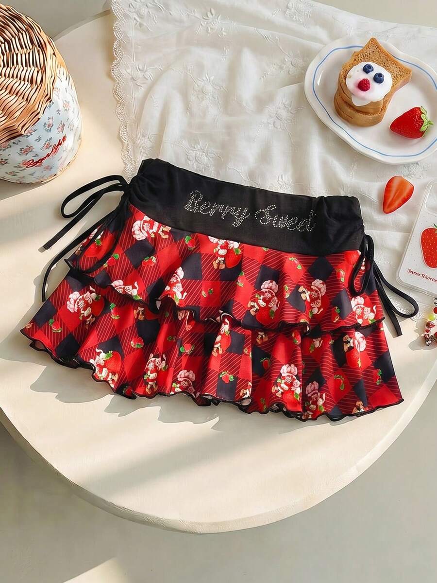 Strawberry Shortcake X SHEIN Jupe mini d'été à la mode pour femmes, avec motif à carreaux, lettres de bande dessinée et ornements de strass - Rouge - Voir 1