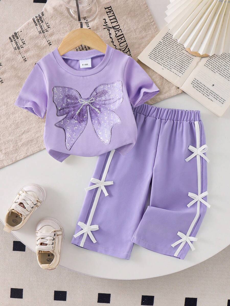 SHEIN Baby Mädchen Sommer süßes Urlaubs Outfit Hellblau Schmetterling Muster T-Shirt & 3D Schleife Dekoration Lila Hose Set Oversized Schleife Kurzarm Kleinkind Trainingsanzug - Violett - Übersicht 1