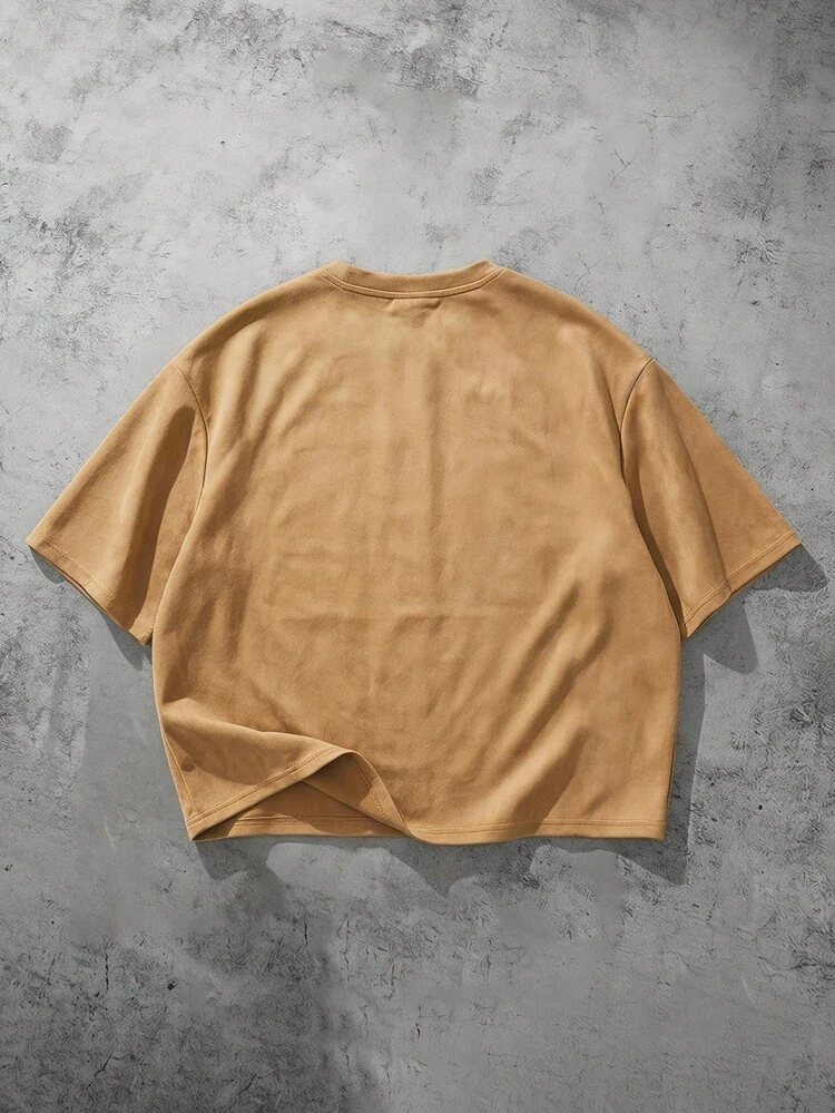 T-shirt col rond à manches courtes, coupe ample, texture daim avec logo de marque, détails de boutons-pression métalliques et coutures raglan