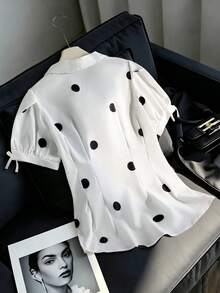 SHEIN Explorewe 這款青少年女孩波點短袖襯衫展現復古法式甜美風格，搭配吸睛的經典大黑白波點。它有翻領和泡泡短袖，袖口裝飾俏皮蝴蝶結。彈性抽褶腰部形成優雅的荷葉邊下擺。將復古魅力與青春活力融合，非常適合外出、度假等場合 - 白色 - 查看 2