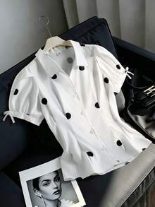 SHEIN Explorewe 這款青少年女孩波點短袖襯衫展現復古法式甜美風格，搭配吸睛的經典大黑白波點。它有翻領和泡泡短袖，袖口裝飾俏皮蝴蝶結。彈性抽褶腰部形成優雅的荷葉邊下擺。將復古魅力與青春活力融合，非常適合外出、度假等場合 - 白色 - 查看 1