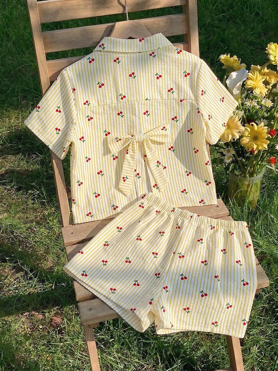 两件套少女套装，奶油色底色，饰以精致竖条纹，俏皮樱桃印花，褶皱质感柔软面料，短袖衬衫配有前扣，后背蝴蝶结镂空设计，搭配同款松紧腰短裤，适合早午餐、约会、户外活动、休闲场合。