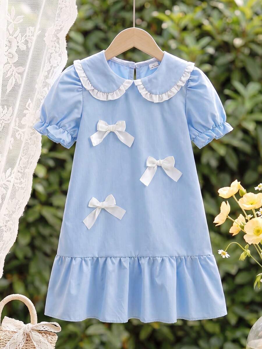 Vintaside Kids Younggirl 春夏淺藍色清新甜美娃娃領泡泡短袖洋裝，風格甜美可愛且具學院風，梭織面料，寬鬆版型，適中厚度，裙身飾有立體白色蝴蝶結，裙襬採荷葉邊設計，增添靈動感與層次感，適合休閒穿著、生日派對、上學等場合