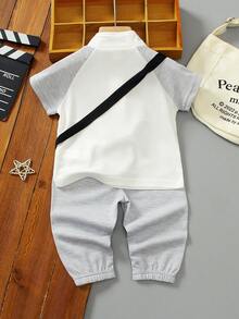 SHEIN 幼童兒童POLO衫短袖2件套，這是一套兒童服裝，整體淺米色，休閒風格，高領半拉鍊，兩側有黑色條紋裝飾，還附帶一個配套的斜挎小包，包包和衣服都有黑馬圖案。下身是慢跑褲，兩側同樣有黑色條紋，整套簡單時尚，適合日常穿著。 - 灰色 - 查看 2