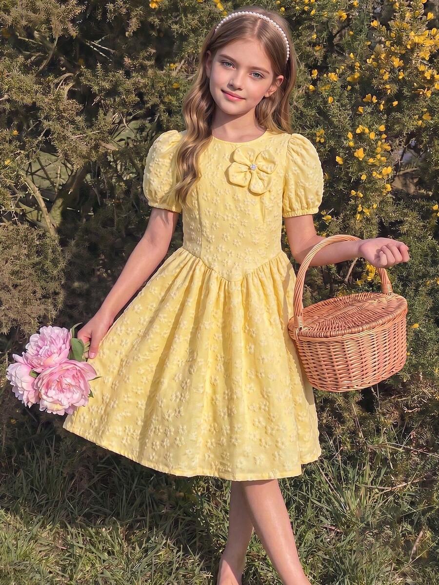 SHEIN Elladie kids 青少年女孩淡黃色3D提花面料，表面覆蓋同色花卉壓花，圓領設計，左胸飾有同色3D花朵飾品，花朵中心鑲嵌小水鑽鈕扣，復古泡泡短袖A字版型洋裝，適合日常上學、假日野餐、朋友聚會、海邊度假