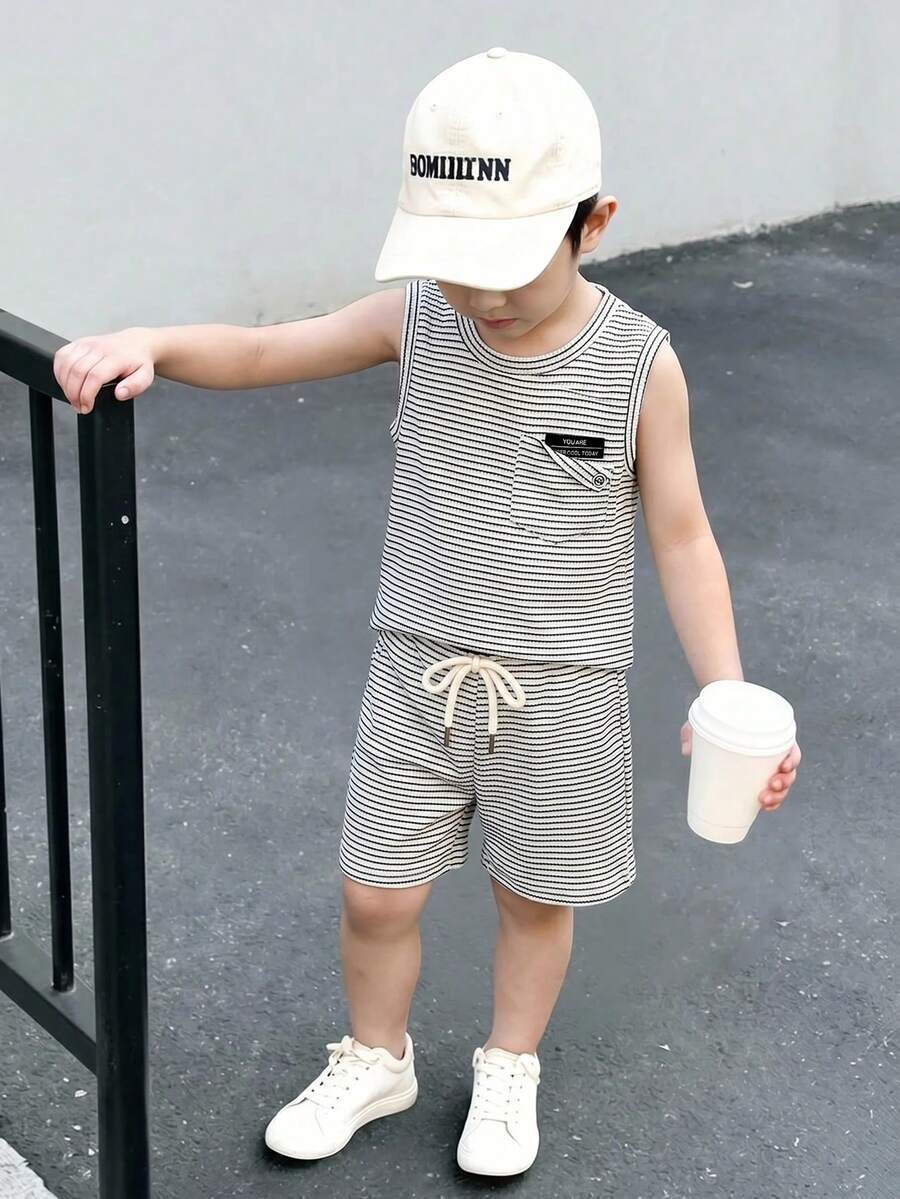SHEIN Vacaura 两件套男童可爱简约休闲运动背心套装,夏季简约休闲时尚无袖背心+短裤两件套针织运动服。上衣采用圆领套头设计,经典简约时尚,胸前不规则口袋饰以贴布和纽扣,打破常规,展现别致风格。裤子为宽松A字版型,配有松紧腰带,饰以黑色贴布和白色抽绳,凸显运动风范。 - 黑與白 - 查看 1