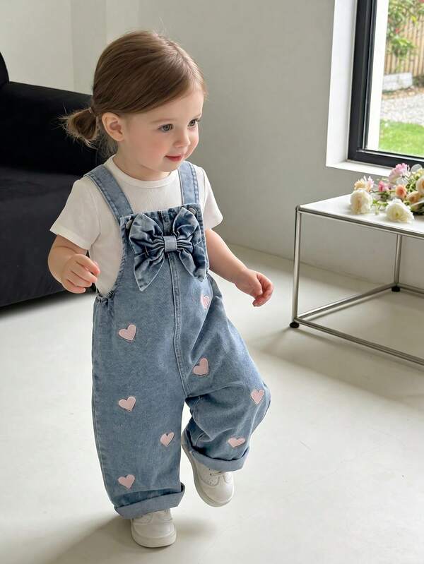 SHEIN Vintaside Kids Overol de mezclilla estilo vintage lindo para niñas, para todas las estaciones, color azul medio, diseño de lazo 3D y bordado de corazón rosa, ajuste de pierna recta holgada, tela suave y cómoda, versátil y a la moda para la escuela, el transporte y el uso al aire libre