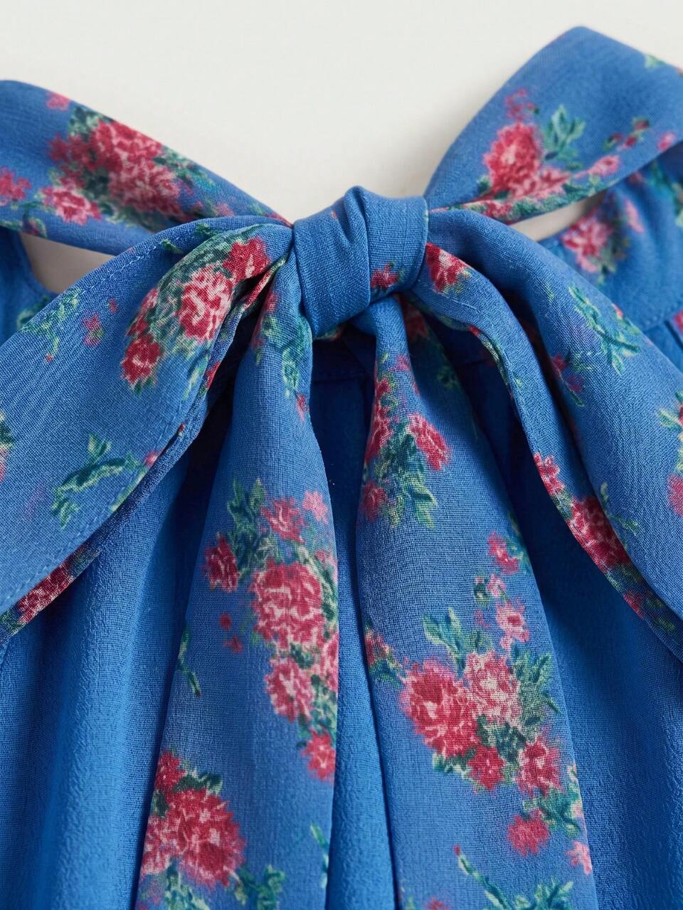 Blusa de gasa con estampado floral azul, ajuste holgado, cuello con lazo posterior, abertura frontal tipo ojo de cerradura y espalda abierta, primavera
