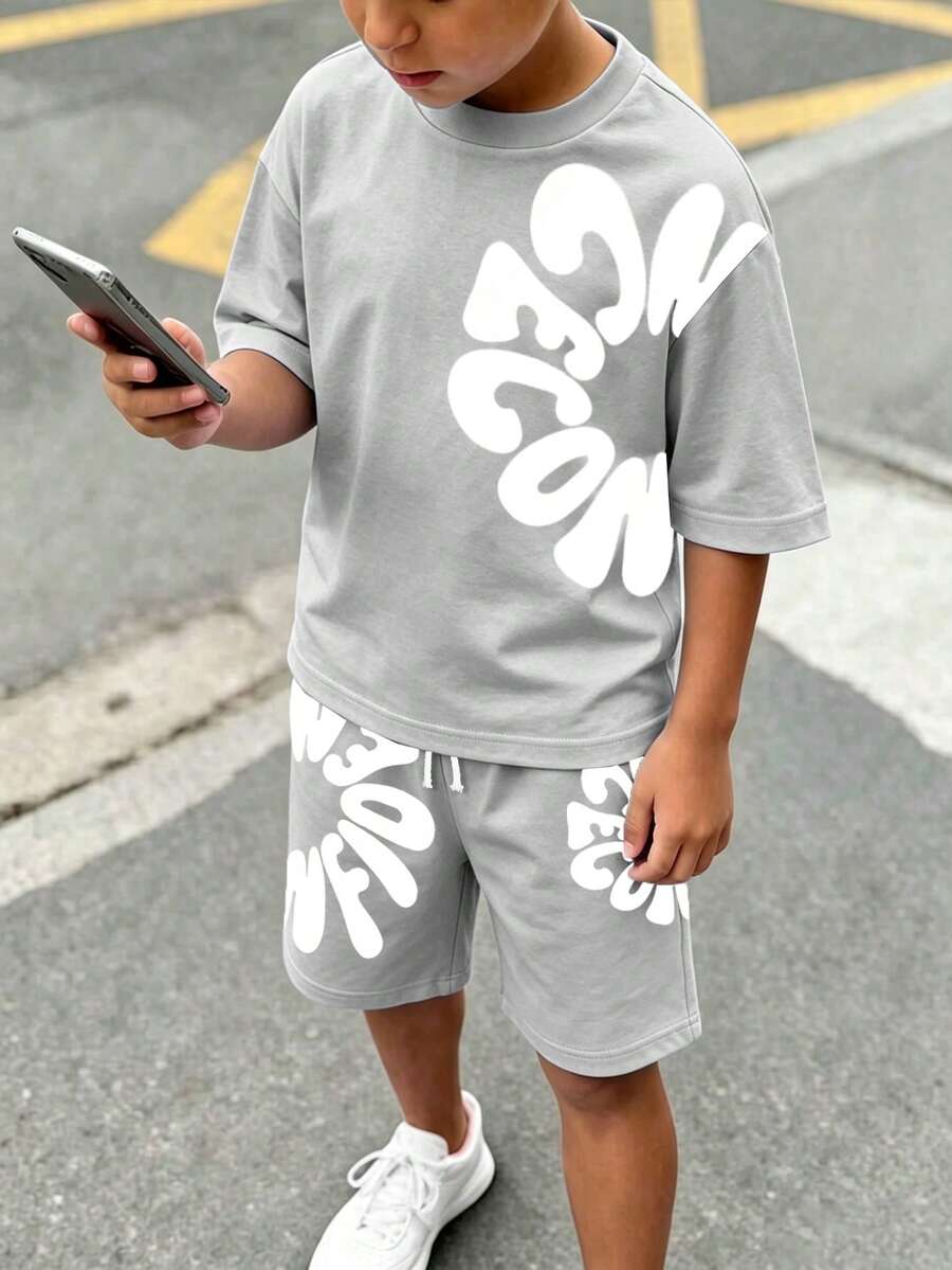 SHEIN 小男孩2件套T恤套裝,幼兒夏季時尚酷炫卡通不對稱字母印花短袖圓領T恤,搭配同款印花鬆緊腰短褲,腰部抽繩裝飾,柔軟彈性面料,寬鬆版型,春夏時尚幼兒T恤套裝,休閒舒適百搭,適合外出與街頭風格 - 淺灰色 - 查看 1