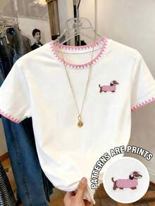 白色底粉色三角飾邊臘腸狗刺繡短袖T恤 - 純白色底，領口與袖口有清新粉色三角鋸齒飾邊，左胸處有可愛臘腸狗刺繡圖案，小狗穿著淺藍色與粉色針織毛衣，俏皮療癒 - 粉色 - 查看 1