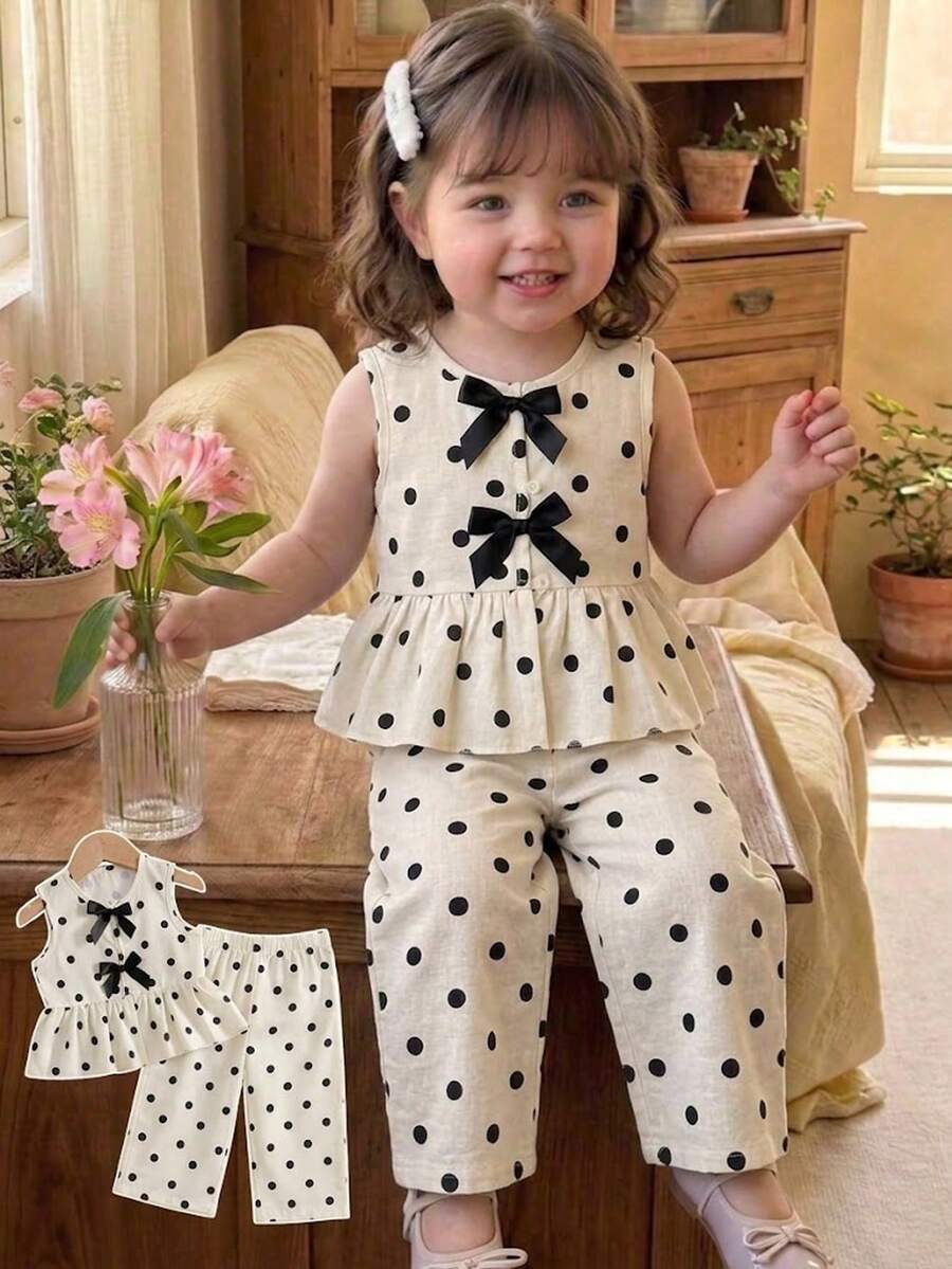 SHEIN Vintaside Kids 2件組女嬰套裝,經典奶油色底色配黑色圓點印花,無袖荷葉邊下擺上衣搭配雙層緞面黑色蝴蝶結,配對寬鬆寬腿褲,平滑輕盈親膚面料,適合日常玩耍、外出與拍照,柔美甜美小女孩穿搭 - 白色 - 查看 1