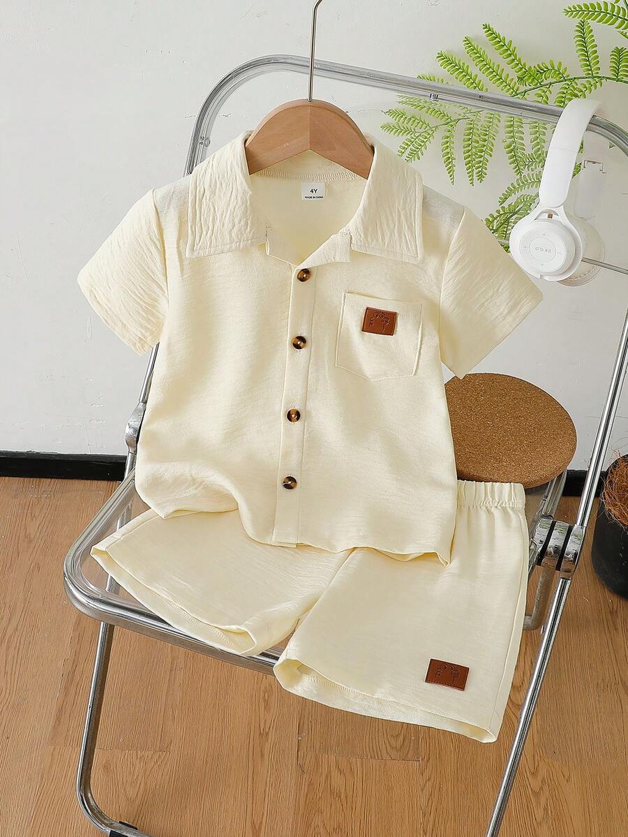 SHEIN 2件組 男童夏季米白色極簡休閒風純色皮革標裝飾翻領短袖襯衫與短褲套裝 生日花童戒童裝 - 米色 - 查看 1