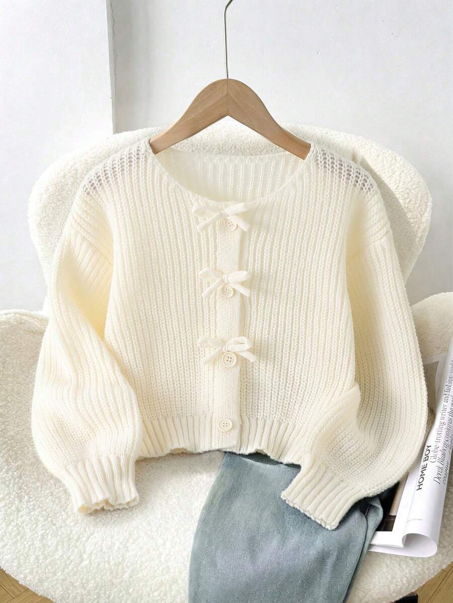SHEIN 1件女童針織開襟衫,時尚簡約圓領3D蝴蝶結鈕扣設計,米色落肩長袖寬鬆休閒風,適中厚度,整齊下擺,緊口袖口,細膩質感,單穿好看,適合日常穿著、居家、外出、上學、旅行,秋冬款 - 米色 - 查看 1
