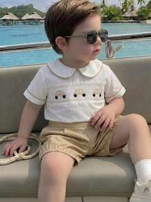 SHEIN Playful Pals 两件套男婴幼儿套装：翻领汽车印花衬衫搭配蓝色梭织短裤，适合派对、婚礼、花童装扮，绅士又可爱。 - 卡其色 - 查看 1
