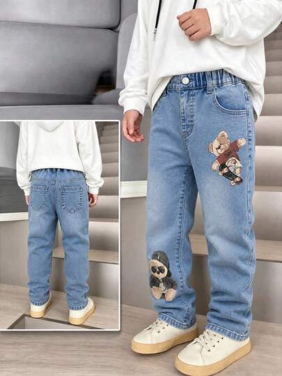 SHEIN Genç Erkek Çocuklar İçin Baskılı Esnek Denim Dar Paça Pantolon, Eğlenceli Çocuksu Moda Kişiselleştirilmiş Okula Dönüş Sezonu Sokak Stili Kombin Önerisi! Klasik Yıkanmış Mavi Denim Esnek Kumaş, Çoklu Elementli Karikatür Baskılar, Yüksek Bel Lastikli Bel Bandı + Sahte Zincir Tasarımı, Sadece Şık Değil Aynı Zamanda Çocukların Bacak Hatlarını Şekillendiren ve En İyi Silüeti Sergileyen Tasarım