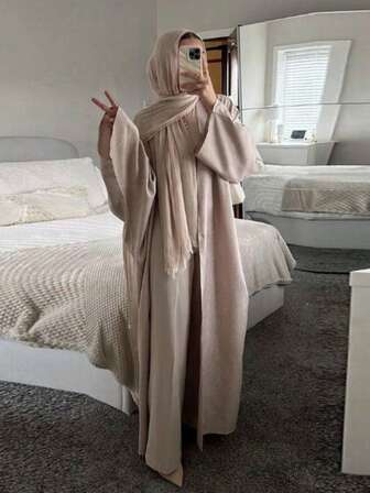 Vestaglia lunga da donna con maniche lunghe e apertura frontale, realizzata in tessuto lavorato a maglia, con maniche raglan e tasche, leggermente elastica