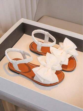 一双白色女童凉鞋新款蝴蝶结公主鞋松紧带设计软底休闲女童沙滩鞋夏季。