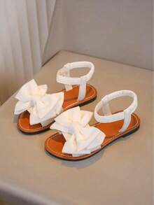 一双白色女童凉鞋新款蝴蝶结公主鞋松紧带设计软底休闲女童沙滩鞋夏季。