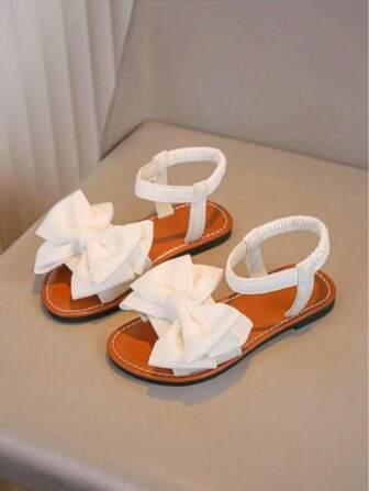 一双白色女童凉鞋新款蝴蝶结公主鞋松紧带设计软底休闲女童沙滩鞋夏季。