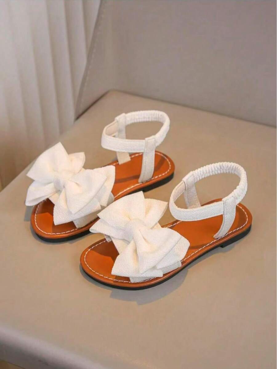 一双白色女童凉鞋新款蝴蝶结公主鞋松紧带设计软底休闲女童沙滩鞋夏季。