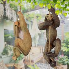 Statue décorative en résine d'un bébé chimpanzé grimpant sur un arbre dans un décor de jardin animal